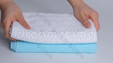 双手特写，把一叠新的浴巾放在床单上。 客房服务员清洁酒店客房